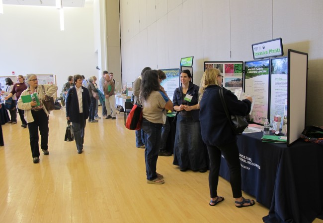 Attendees discuss invasive plant topics with the exhibitors.